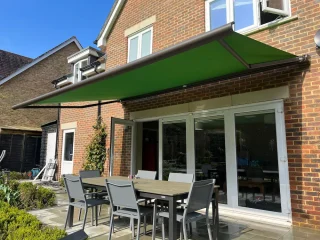 Green awning over sunny garden furniture